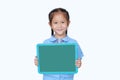 Cheerful Asian little child girl in school uniform holding blank board over white background. Kid with empty green blackboard. Royalty Free Stock Photo