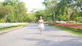 Cheerful asian little girl in white dress running on road in garden