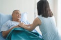 Cheerful asian nurse smiling and covering a blanket to elderly in nursing home Royalty Free Stock Photo