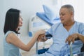 Cheerful asian nurse smiling and talking with elderly patient in the room Royalty Free Stock Photo