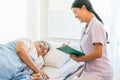 Cheerful Asian nurse talking with elderly patient for monitoring and check up. nurse giving consoling to senior and encourage. Royalty Free Stock Photo