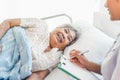 Cheerful Asian nurse talking with elderly patient for monitoring and check up. Royalty Free Stock Photo