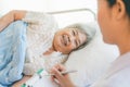 Cheerful Asian nurse talking with elderly patient for monitoring and check up. Royalty Free Stock Photo