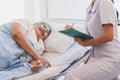 Cheerful Asian nurse talking with elderly patient for monitoring and check up. Royalty Free Stock Photo