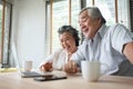 Cheerful Asian Senior couple having video chat with their family on Laptop computer on table at home Royalty Free Stock Photo