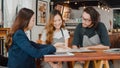 Cheerful Asian small business owners couple meeting with consultant talking about business plan and finance in cafe. Young Royalty Free Stock Photo