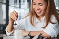 Cheerful Asian woman eating a peace of coconut cream cake in living room Royalty Free Stock Photo