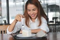 Cheerful Asian woman eating a peace of coconut cream cake in living room Royalty Free Stock Photo