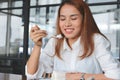 Cheerful Asian woman eating a peace of coconut cream cake in living room Royalty Free Stock Photo