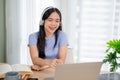 A cheerful Asian woman enjoys chatting with her friend online through a video call on her laptop Royalty Free Stock Photo