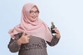 cheerful Asian woman with hijab, holding and showing a small pots of succulent cactus plants. Isolated image on blue