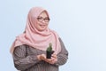 cheerful Asian woman with hijab, holding and showing a small pots of succulent cactus plants. Isolated image on blue