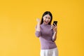 A cheerful Asian woman is showing clenched fist and looking at her smartphone with a happy face Royalty Free Stock Photo