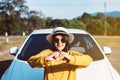 Cheerful asian woman showing hand heart shape while standing with new car on road,Happy and smiling,Car insurance concept