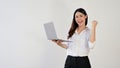 A cheerful Asian woman shows her fist while holding her laptop. success, celebrating Royalty Free Stock Photo