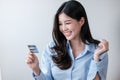 Cheerful Asian woman with smart phone and credit card, she fills in credit card information to pay for goods and Royalty Free Stock Photo