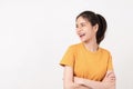 Cheerful Asian woman standing with arms folded and smiling in wearing a yellow shirt, Looking to the side. Royalty Free Stock Photo