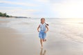 Cheerful Asian young girl child having fun running on tropical sand beach at sunrise Royalty Free Stock Photo