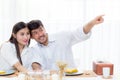 Cheerful asian young man and woman having sitting lunch and talking together pointing someting