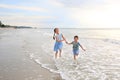 Cheerful Asian young sister and little brother having fun together on tropical sand beach at sunrise. Happy family boy and girl Royalty Free Stock Photo