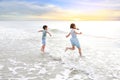 Cheerful Asian young sister and little brother having fun together on tropical sand beach at sunrise. Happy family boy and girl Royalty Free Stock Photo