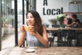 Cheerful asian young woman drinking warm coffee or tea enjoying it while sitting in cafe. Royalty Free Stock Photo