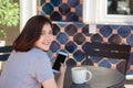 Cheerful asian young woman sitting in cafe drinking coffee and using smartphone for talking, reading and texting. Royalty Free Stock Photo