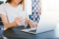 Cheerful asian young woman sitting in cafe drinking coffee and using smartphone for talking, reading and texting. Royalty Free Stock Photo