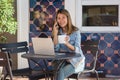 Cheerful asian young woman sitting in cafe drinking coffee and using smartphone for talking, reading and texting. Royalty Free Stock Photo