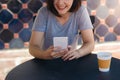 Cheerful asian young woman sitting in cafe drinking coffee and using smartphone for talking, reading and texting. Royalty Free Stock Photo