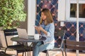 Cheerful asian young woman sitting in cafe drinking coffee and using smartphone for talking, reading and texting. Royalty Free Stock Photo