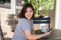 Cheerful asian young woman sitting in cafe drinking coffee and using smartphone for talking, reading and texting. Royalty Free Stock Photo