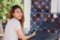 Cheerful asian young woman sitting in cafe drinking coffee and using smartphone for talking, reading and texting. Attractive asian Royalty Free Stock Photo