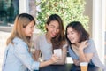 Cheerful asian young women sitting in cafe drinking coffee with friends and talking together.