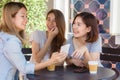 Cheerful asian young women sitting in cafe drinking coffee with friends and talking together.