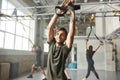 Too fit to quit. Cheerful athletic man doing fitness TRX training exercises at industrial gym Royalty Free Stock Photo