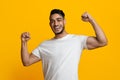 Cheerful athletic middle eastern man showing his muscles