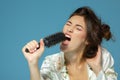 Cheerful attractive teen girl sing song holding comb like a microphone in the morning, over blue