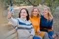 Cheerful attractive three young women best friends having fun together outside and making selfie. Royalty Free Stock Photo