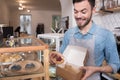 Cheerful attractive waiter putting cakes into the box. Royalty Free Stock Photo