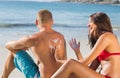 Cheerful attractive woman applying sun cream on her boyfriends b Royalty Free Stock Photo