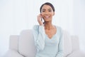 Cheerful attractive woman on the phone sitting on cosy sofa Royalty Free Stock Photo