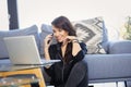 Cheerful attractive woman using mobile phone and laptop while relaxing at home Royalty Free Stock Photo