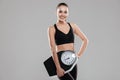 Cheerful attractive young woman athlete standing and holding weighing scale Royalty Free Stock Photo