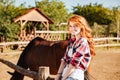 Cheerful attractive young woman cowgirl with horse in village Royalty Free Stock Photo