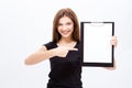 Cheerful attractive young woman showing clipboard and pointing on it Royalty Free Stock Photo