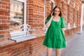 Cheerful attractive young woman talking on mobile phone walking on city street in sunny summer day. Royalty Free Stock Photo