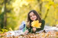 Cheerful autumn teen with long healthy hair holding yellow maple leaf outdoors in sunny day. Beautiful teenager in fall