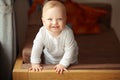 Cheerful baby with cute friendly smile stands on couch