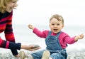 Cheerful baby girl and her mother playing on the beach Royalty Free Stock Photo